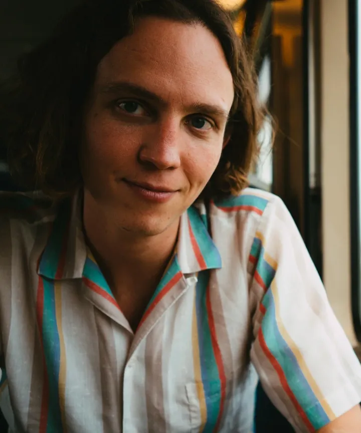 Charlie Cross, seated by a train window, smiling at the camera